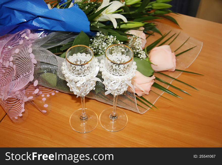 Two beautiful decorated wedding glasses and flowers on table; top view. Two beautiful decorated wedding glasses and flowers on table; top view