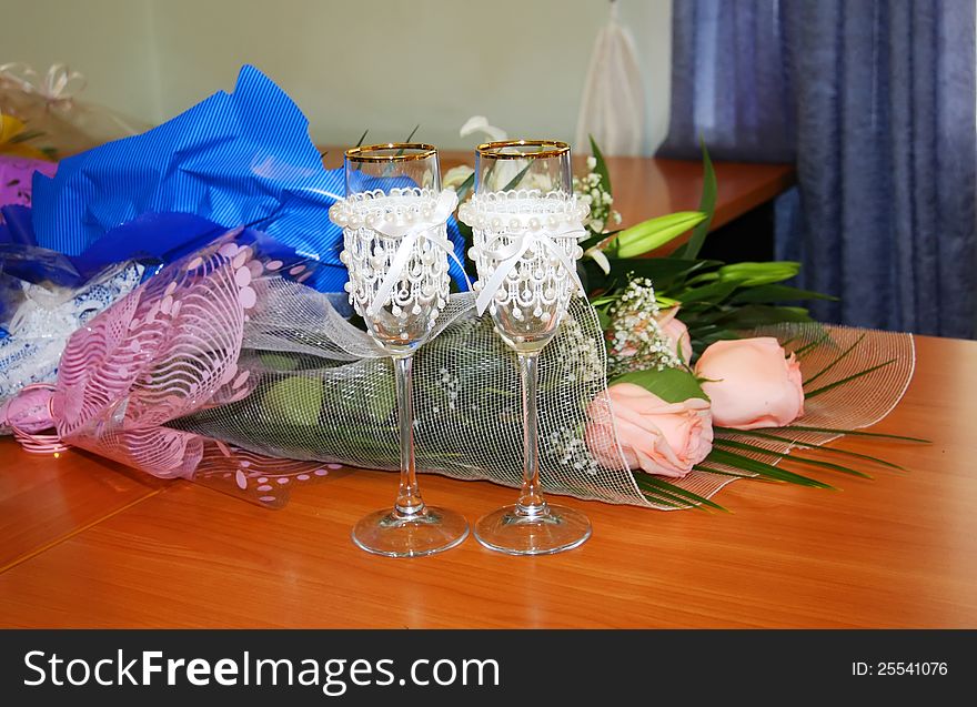 Two beautiful decorated wedding glasses and flowers on table. Two beautiful decorated wedding glasses and flowers on table