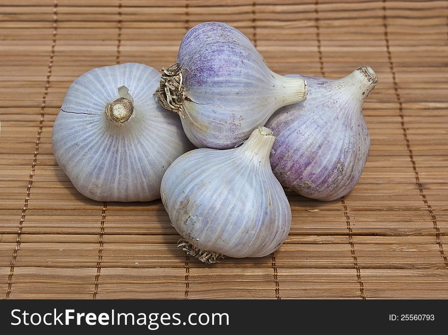 Four garlic on wood background