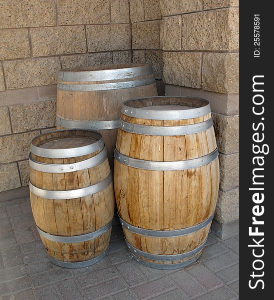 Three new wooden barrels with shiny hoops in front of the corner of a modern concrete block building.  Room for copy or text. Three new wooden barrels with shiny hoops in front of the corner of a modern concrete block building.  Room for copy or text.