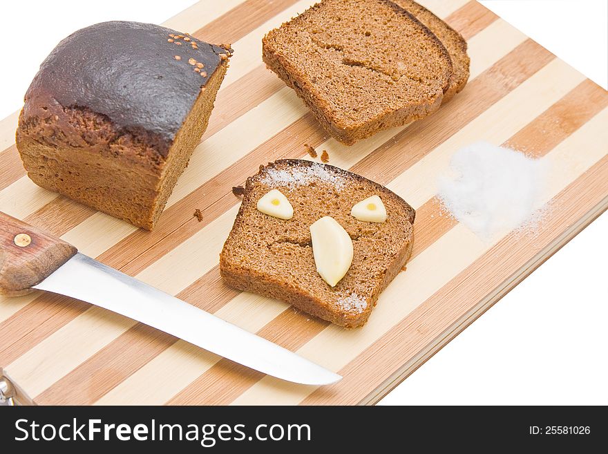 Sliced bread with the chunk and knife on a kitchen board, with a scary face made of bread and garlic. Sliced bread with the chunk and knife on a kitchen board, with a scary face made of bread and garlic.