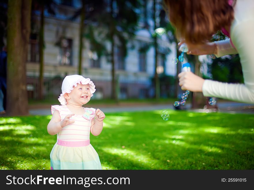 Mother and daughter playing with soup bubbles outdoors