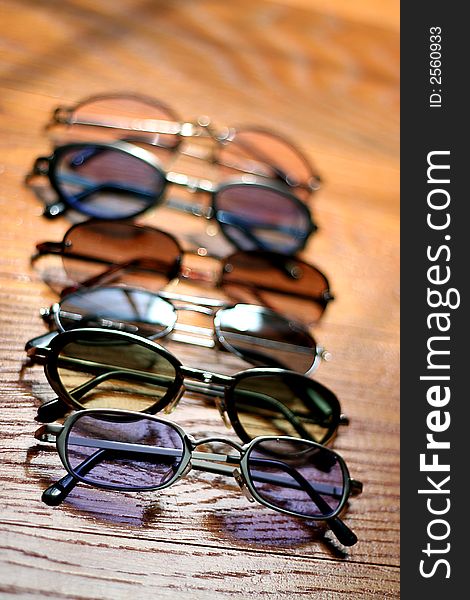 Row of Different Colored Sunglasses on Wooden Floor. Row of Different Colored Sunglasses on Wooden Floor