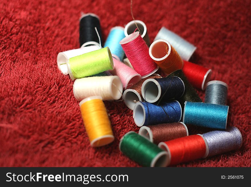 Rows of Different Colored Spools of Thread on Red Towel. Rows of Different Colored Spools of Thread on Red Towel