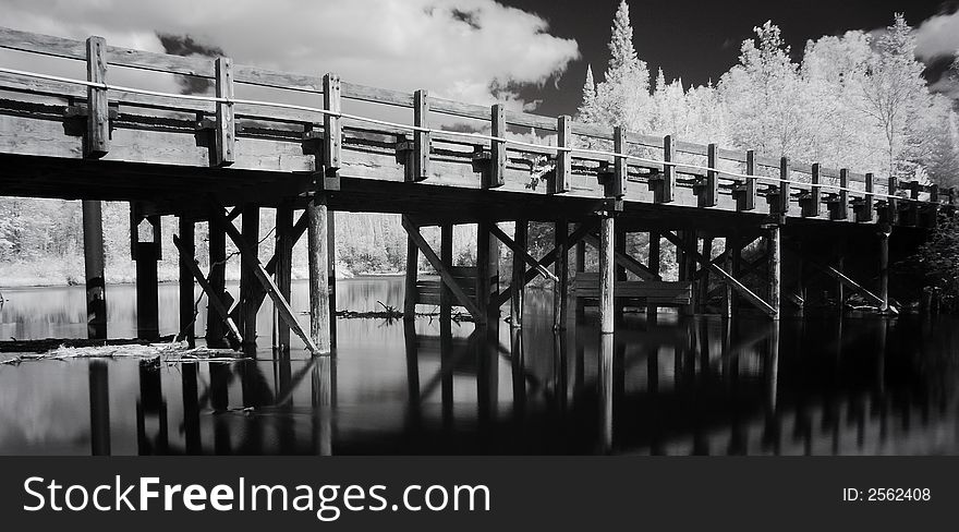 A wooden bridge over a gently flowing river in northern Minnesota in infrared. A wooden bridge over a gently flowing river in northern Minnesota in infrared.