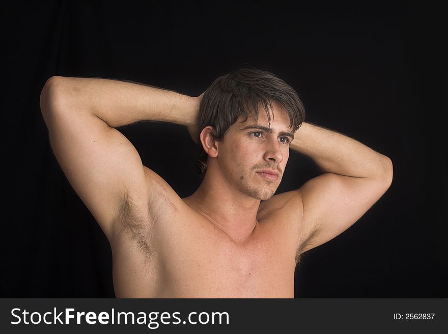 Portrait of young man standing with no shirt on over black background