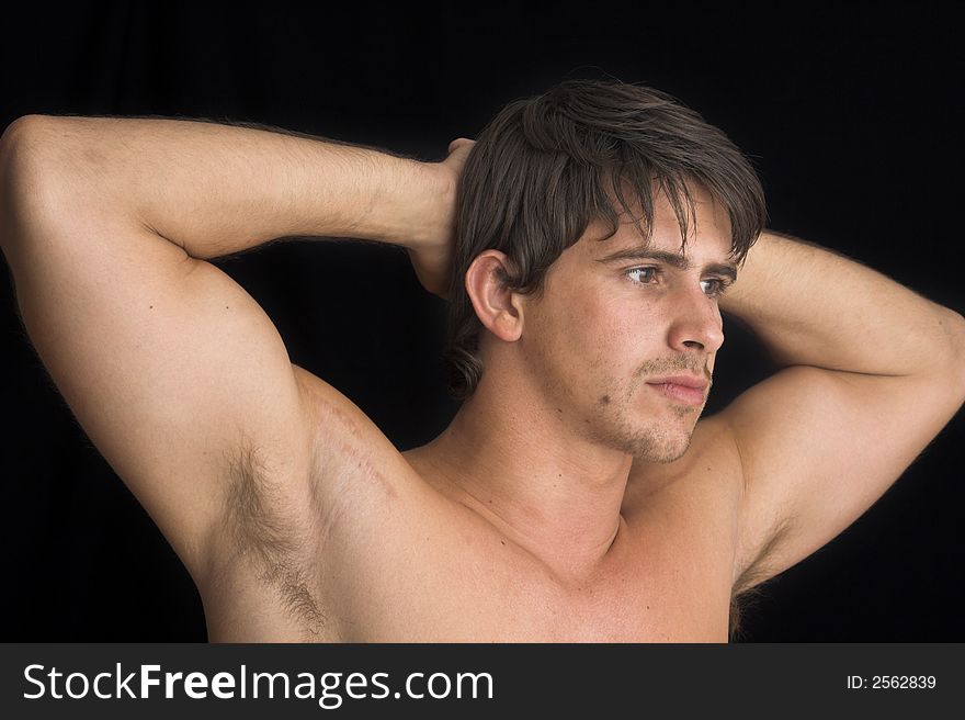 Portrait of young man standing with no shirt on over black background