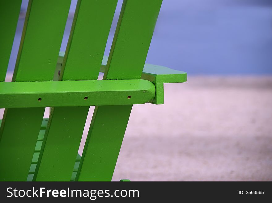 A bright green beach chair breaks the monotone stretch of a tropical beach. A bright green beach chair breaks the monotone stretch of a tropical beach