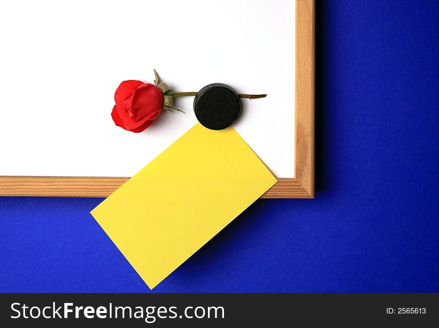 Whiteboard with empty yellow post-it note and magnet in the form of a hart. Whiteboard with empty yellow post-it note and magnet in the form of a hart