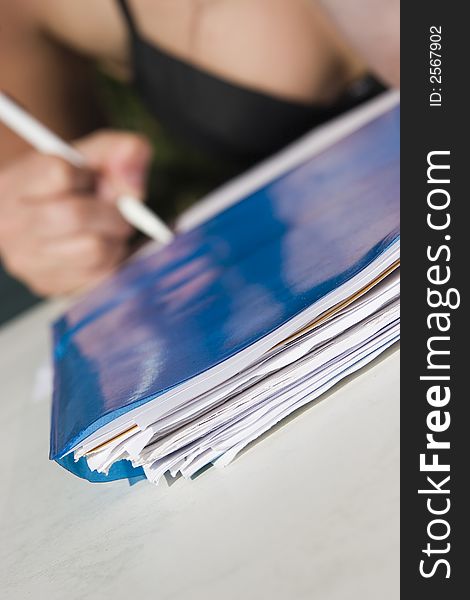 Stack of papers on the front and pencil in hand on background. Stack of papers on the front and pencil in hand on background