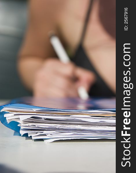 Stack of papers in front and pencel in hand in background. Stack of papers in front and pencel in hand in background