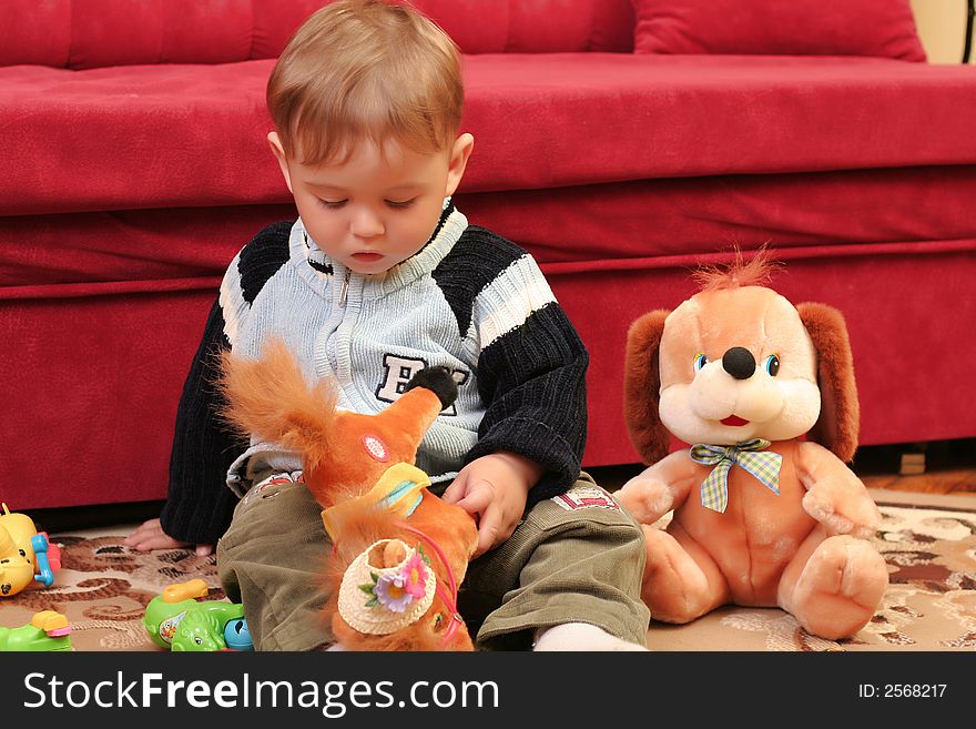 Little blond baby boy playing with toys at home