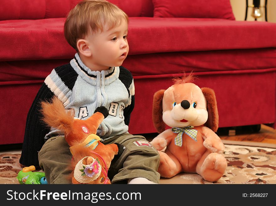 Little blond baby boy playing with toys at home