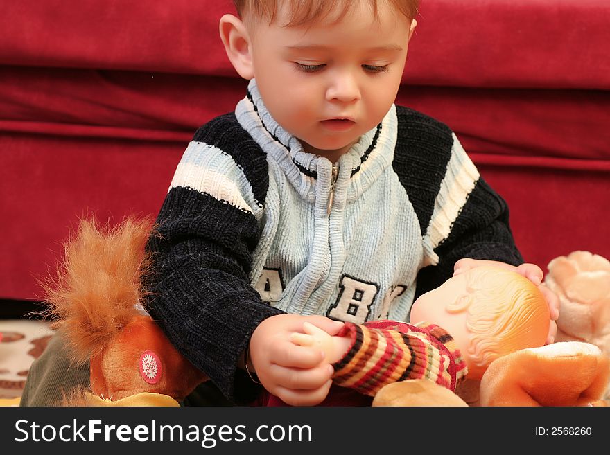 Little blond baby boy playing with toys at home