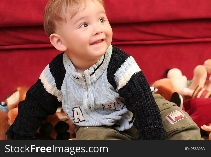 Little blond baby boy playing with toys at home