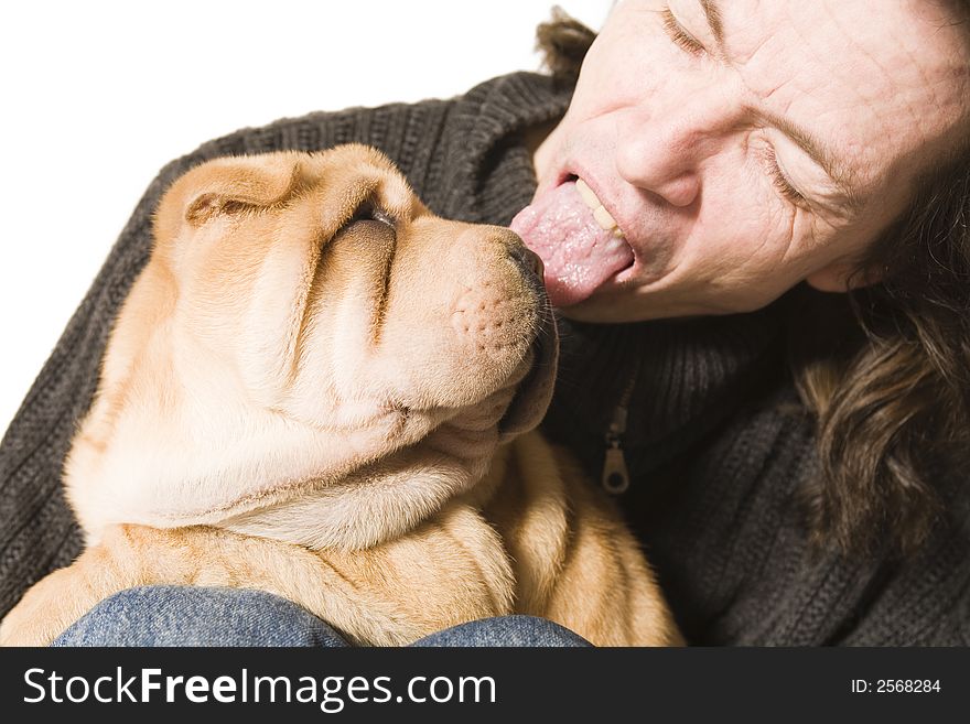 A funny young man licking a sharpei puppy over the head. A funny young man licking a sharpei puppy over the head