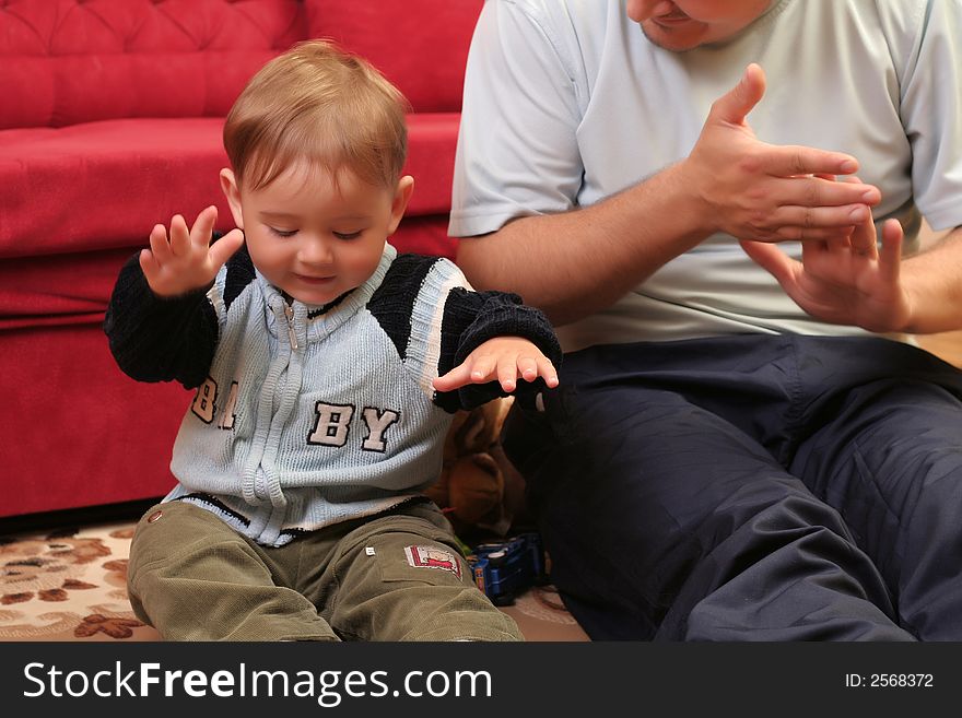 Little blond baby boy playing with his father at home