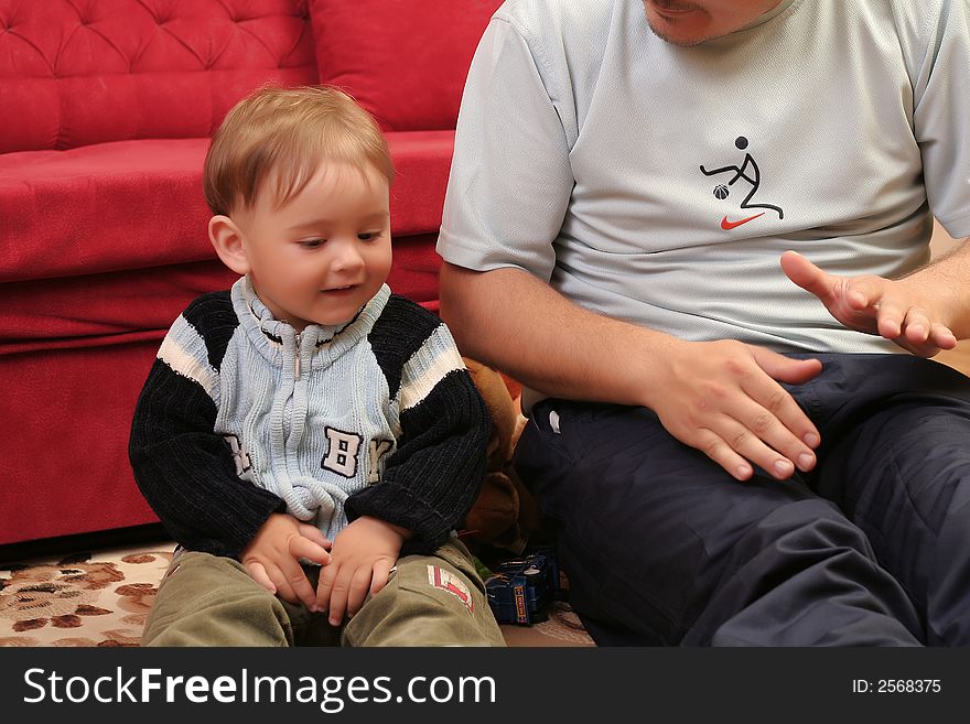 Little blond baby boy playing with his father at home