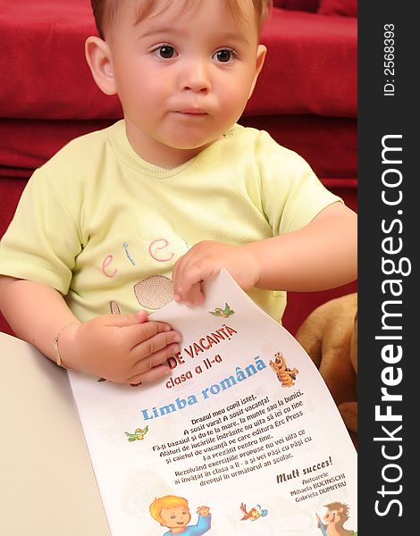 Expressive little blond baby boy gesticulate while reading a child book