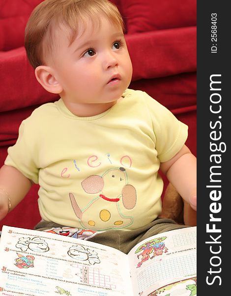 Expressive little blond baby boy gesticulate while reading a child book