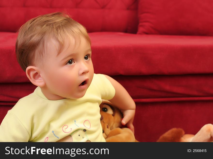 Expressive little blond baby boy gesticulate while playing with toys