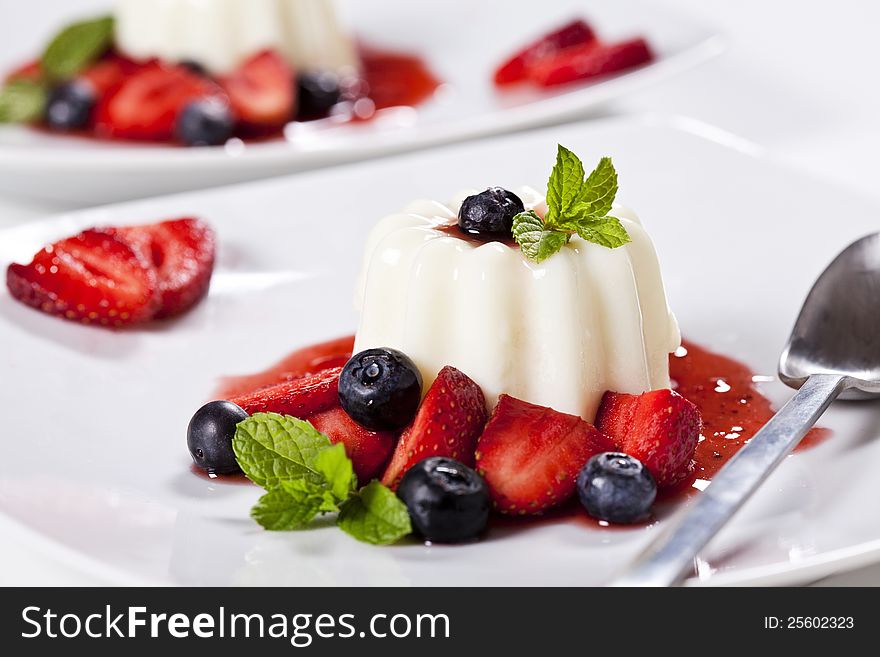 Close up photograph of a panna cotta dessert with strawberries and blueberries. Close up photograph of a panna cotta dessert with strawberries and blueberries