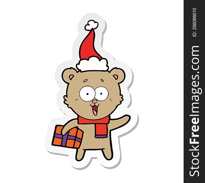 laughing teddy  bear with christmas present wearing santa hat