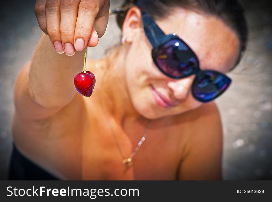 Two sweet cherries in hands at the beautiful girl