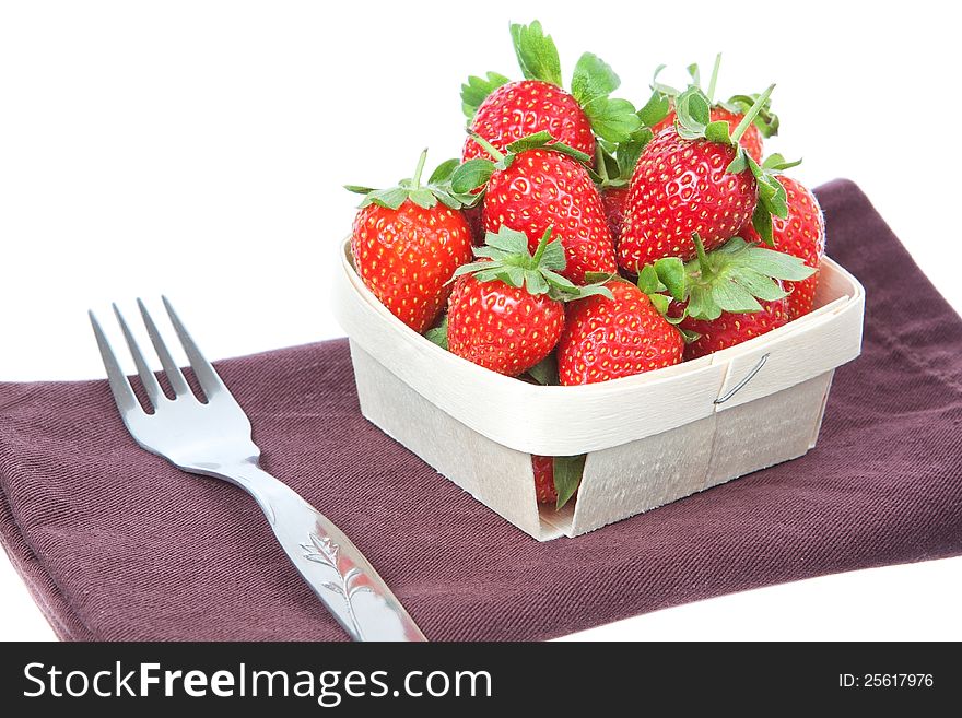 The composition of strawberries in a basket and a fork. On a white background.