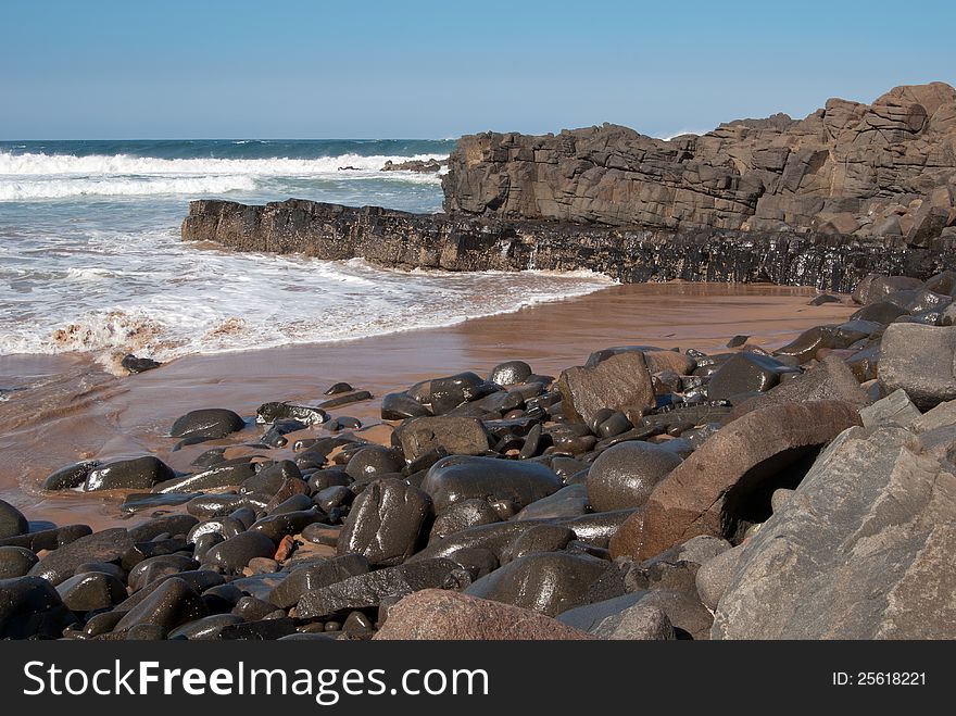 Wet boulders gleaming in the sun after the waves have washed over them on a beach at Ballito, KwaZulu-Natal North Coast, South Africa. Wet boulders gleaming in the sun after the waves have washed over them on a beach at Ballito, KwaZulu-Natal North Coast, South Africa