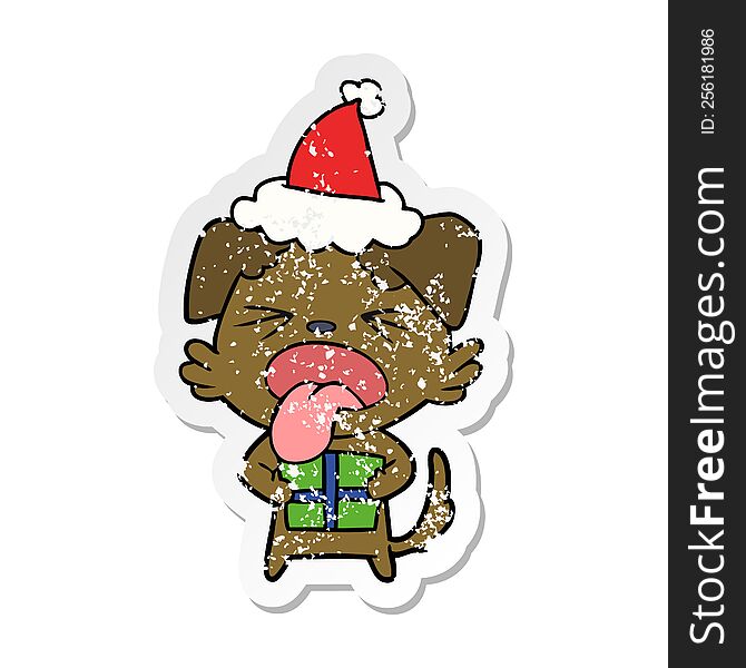 hand drawn distressed sticker cartoon of a dog with christmas present wearing santa hat