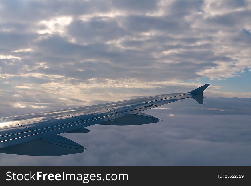 Plane wing with clouds in the sky.