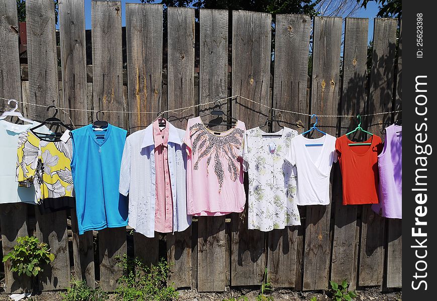 The photo of sold clothes hanged on a wooden fence. The photo of sold clothes hanged on a wooden fence