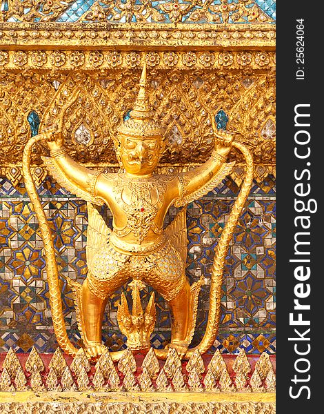 The statue of Garuda battling naga serpent on the wall of temple in Thailand. The statue of Garuda battling naga serpent on the wall of temple in Thailand