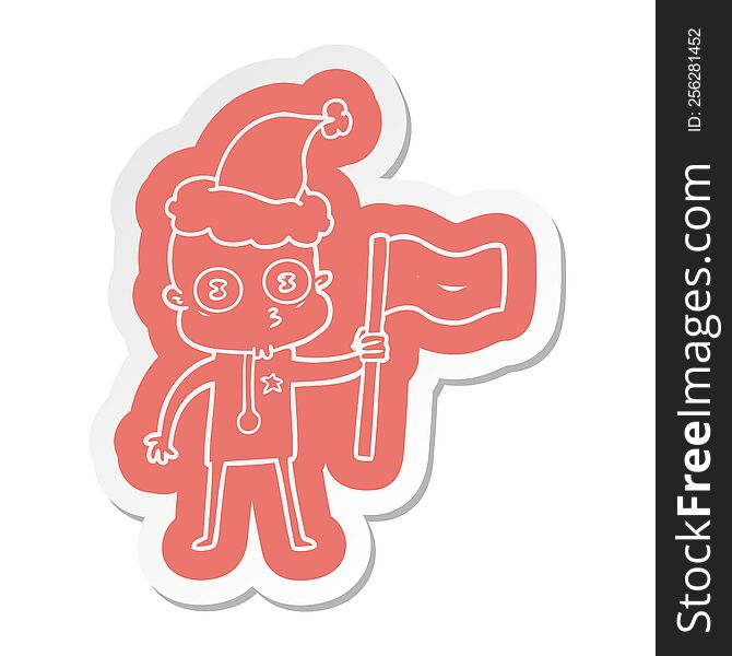 quirky cartoon  sticker of a weird bald spaceman with flag wearing santa hat