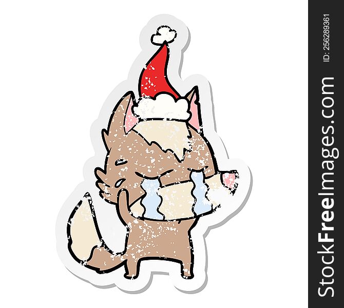 hand drawn distressed sticker cartoon of a crying wolf wearing santa hat