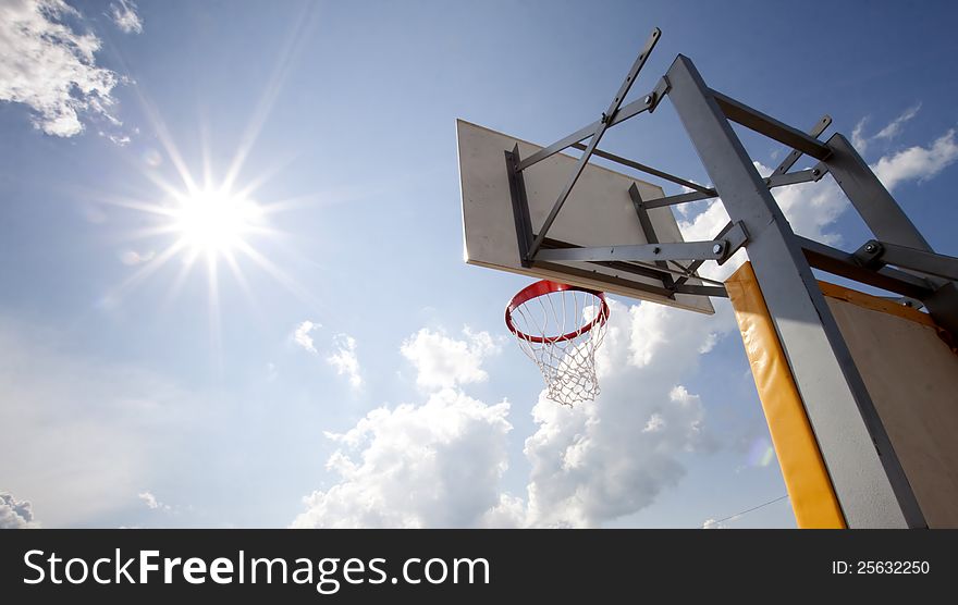 Basketball hoop with blue sky and sun