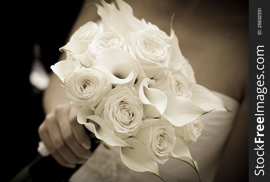 Bride holding white wedding bouquet - sepia