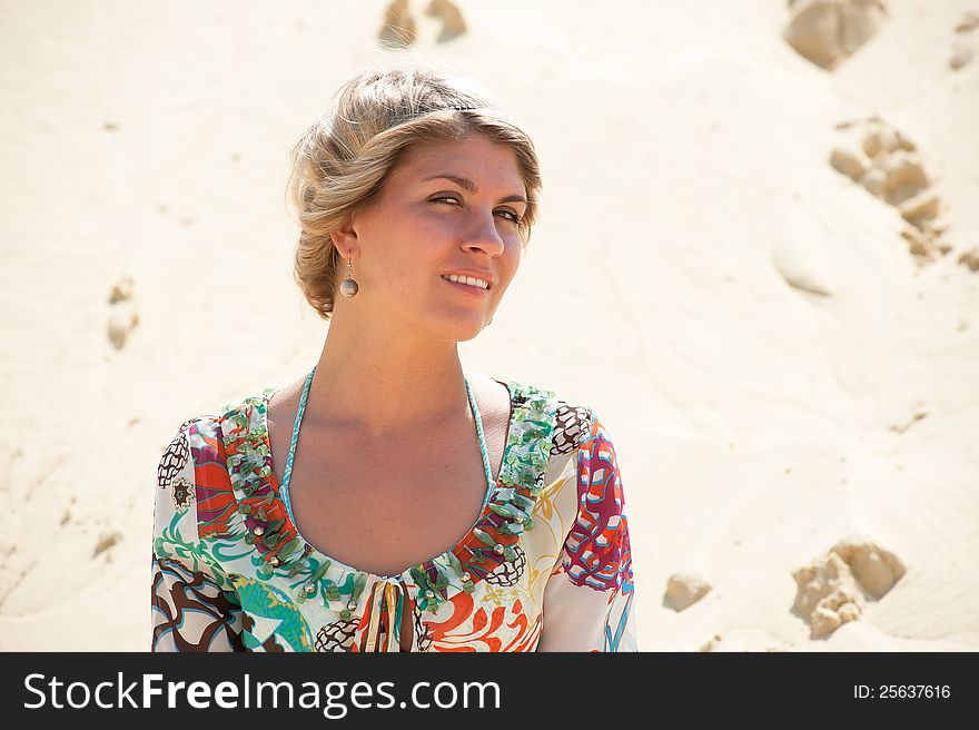 Portrait of a blonde in a sarafan on the background the sand