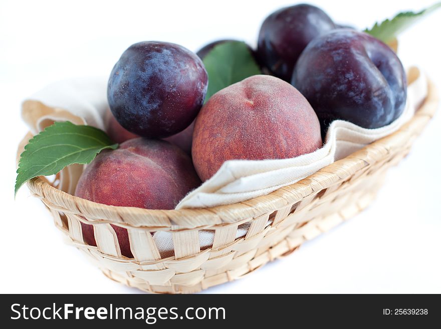 Ripe peaches and plums in the basket, closeup