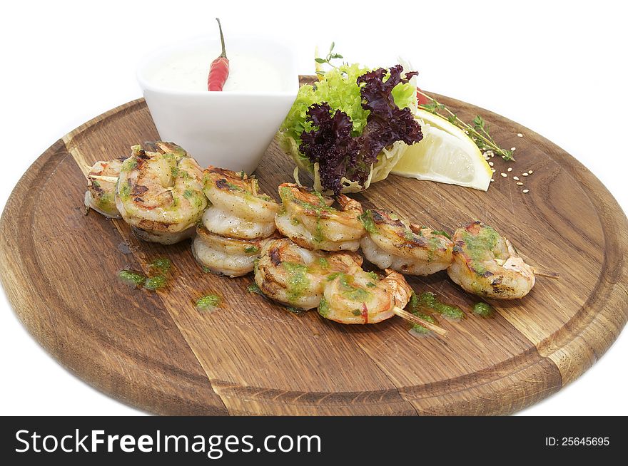 Skewers of shrimp with herbs on a wooden plate