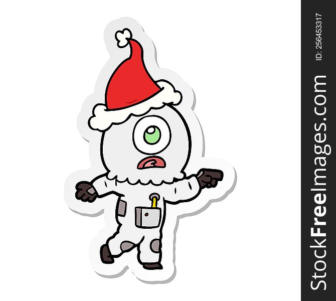 Sticker Cartoon Of A Cyclops Alien Spaceman Pointing Wearing Santa Hat