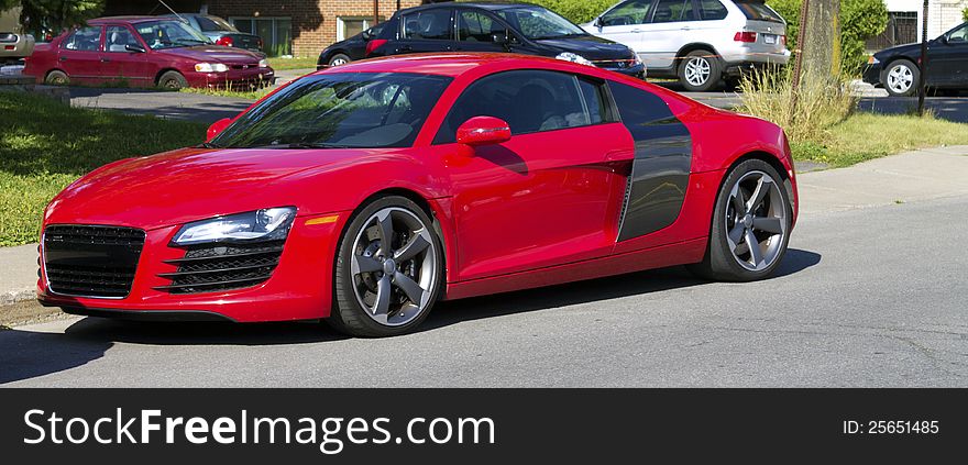 A german made modern red sprotcar parked on the street. A german made modern red sprotcar parked on the street