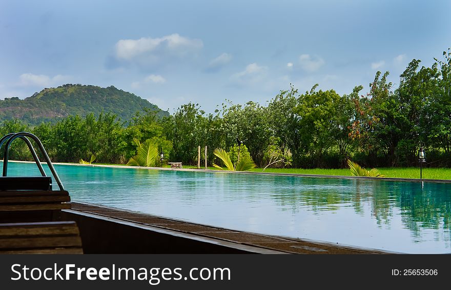 Beautiful refreshing calm blue pool with reflections backed by tropical vegetation. Beautiful refreshing calm blue pool with reflections backed by tropical vegetation