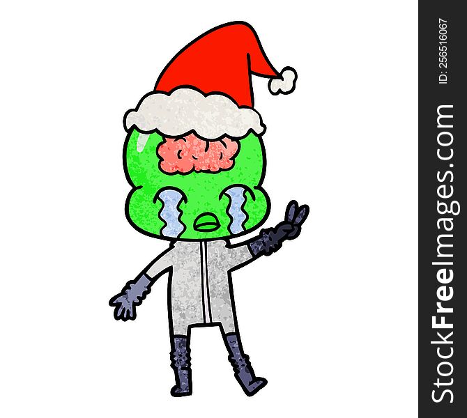 hand drawn textured cartoon of a big brain alien crying and giving peace sign wearing santa hat