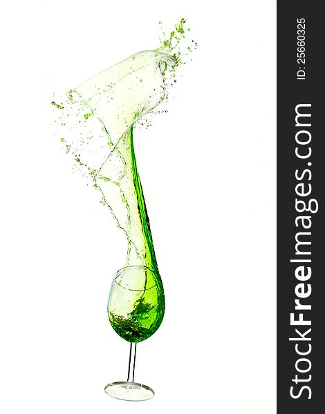 A wine glass spilling green liquid upwards. A wine glass spilling green liquid upwards