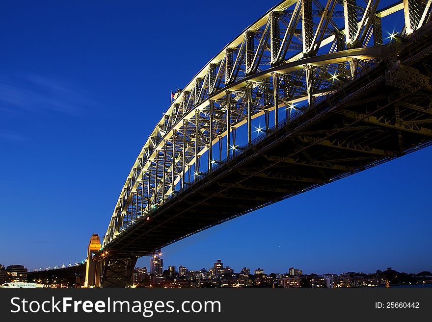 Sydney Harbour Bridge taken at dusk, where the sky is rich blue and where the north shore is visible