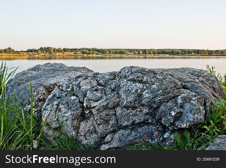 Sky, stone and green trees in nature over lake with reflections