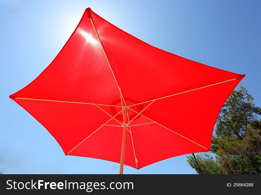 A red sun umbrella opened up on a sunny day