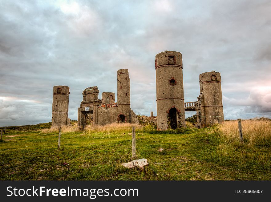 Old stone ruins of a castle or house or mansion in medievel France with a dramatic grey cloudy sky in the background and bright green grass in the foreground. This is a high dynamic range image. Old stone ruins of a castle or house or mansion in medievel France with a dramatic grey cloudy sky in the background and bright green grass in the foreground. This is a high dynamic range image.